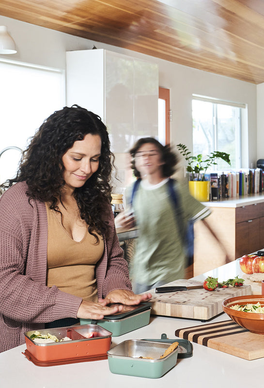Mom and son making lunches in kitchen in steel lunch boxes